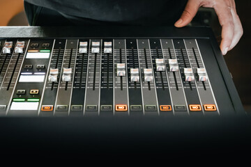 Top view of the faders of a professional audio mixer with the hands of a sound engineer ready to...