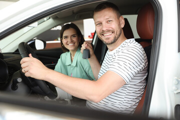 Happy family with keys inside new car