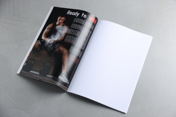 Open magazine on light grey table. Mockup for design