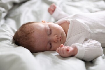 Cute newborn baby sleeping on bed, closeup