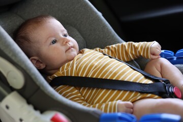 Cute little baby fastened in car seat