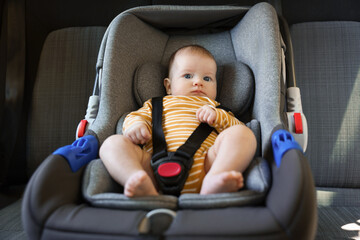 Cute little baby fastened in car seat