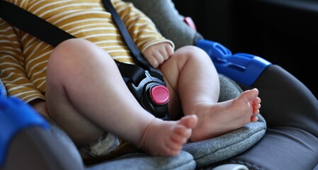 Cute little baby fastened in car seat, closeup