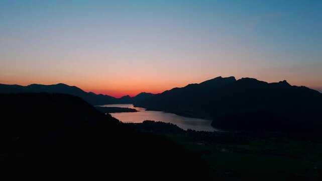 Beautiful orange afterglow of a sunset over Lake Wolfgang and the town of Strobl.