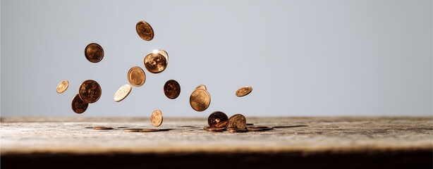 Falling Coins on Wooden Surface: A collection of golden coins cascades through the air, landing on a weathered wooden surface, signifying wealth and financial flow.