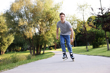 Young man roller skating in park on summer day