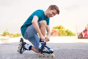 Happy man putting on roller skates outdoors