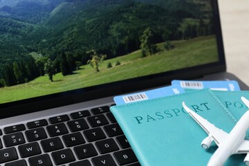 Passports, flight tickets, plane model and laptop on table, closeup