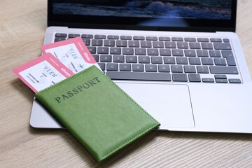 Passport, tickets and laptop on light wooden table, closeup