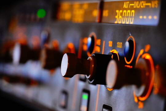 Airplane cockpit control panel with glowing buttons and knobs