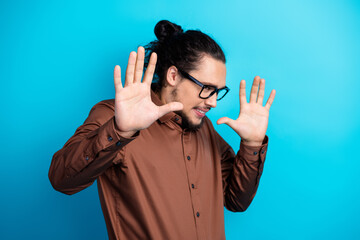 Confident young man making expressive gestures against a teal background, wearing formalwear