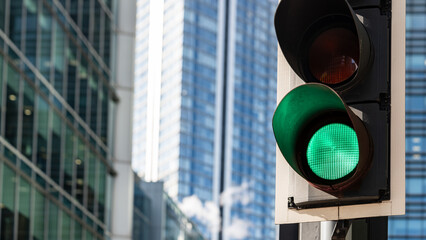 Green traffic light illuminated against modern glass buildings