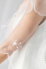 Elegant bridal veil on a young girl, seen from behind, against a soft grey studio backdrop