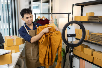A man is selling clothes online. He has a notebook to record information. He is wearing a blue...