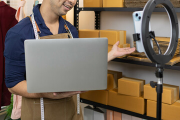 A man is selling clothes online. He has a notebook to record information. He is wearing a blue...