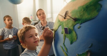 Ecology STEM Class: Elementary School Boy Attaching Miniature Model of Wind Turbine to Globe....
