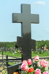 Marble cross in a serene cemetery. In the embrace of nature a granite cross stands as a testament...