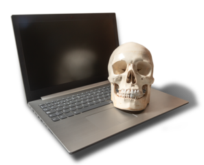 Imagen creativa de tecnología y mortalidad con un cráneo humano sobre un ordenador portátil apagado. Imagen aislada en formato PNG con fondo transparente.