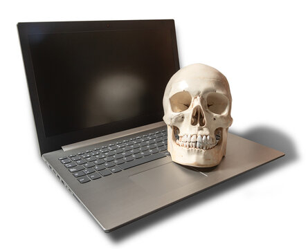Imagen creativa de tecnolog&iacute;a y mortalidad con un cr&aacute;neo humano sobre un ordenador port&aacute;til apagado. Imagen aislada en formato PNG con fondo transparente.