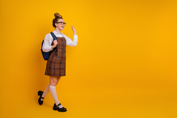 Fototapeta premium Charming young student posing on vibrant yellow background wearing stylish uniform, showcasing youthful energy and cheerfulness
