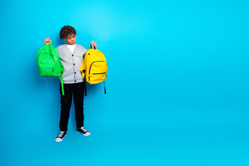 Child holding colorful backpacks, ready for school with a vibrant blue background highlighting...
