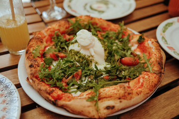 Freshly baked pizza topped with creamy burrata, tomatoes and fresh rucola leaves