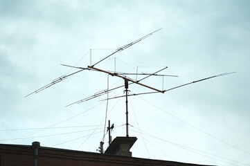 Old big antenna on the roof of a brick house against the sky, in the city