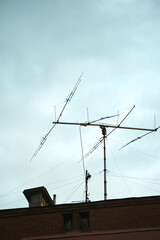 Old big antenna on the roof of a brick house against the sky, in the city