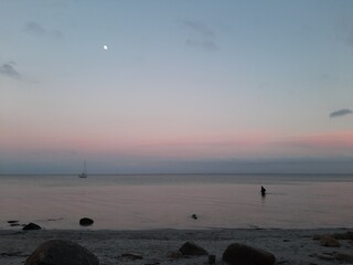 Strandlandschaft mit Meer, Angler und Boot in der Abenddämmerung an der Ostsee