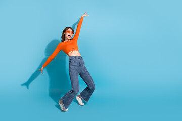 Young woman in casual and trendy style posing joyfully against a blue background, expressing...