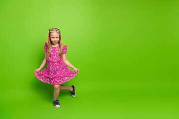 A charming young girl in a floral pink dress posing against a vibrant green background, showcasing...