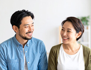 室内で笑顔で会話する若い夫婦のライフスタイルイメージ｜カップル,コミュニケーション,日常,暮らし