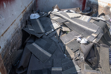 Roofing shingles damaged by hailstorm in garbage bin