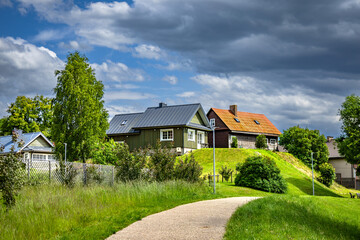Fototapeta premium Scandinavian style Village Houses with Colorful Roofs and Gravel Path Under Dramatic Cloudy Sky