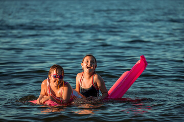 Girls splashing in the sea. Children playing in the water during summer vacation. Family holiday by the sea. Active leisure time
