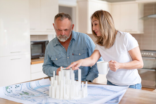 Couple discussing architectural model in modern kitchen while planning their future home development project