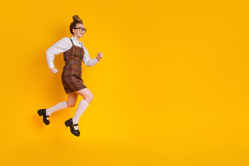 Fototapeta na wymiar Dynamic young student in stylish uniform jumping against a bright yellow background, showcasing youthful energy and positivity.