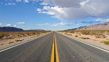 Fototapeta premium Long desert road stretches through Nevada landscape with mountains under a partly cloudy sky inviting a scenic drive.