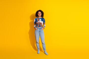 Fototapeta premium Smiling young woman in casual outfit against bright yellow background radiating joy and confidence