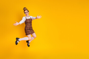 Cheerful young woman in fashionable academic uniform posing with enthusiasm against a vibrant...