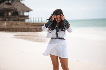 Beach holiday fashion, young woman on a white sandy beach