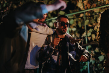 A group of friends in an outdoor setting, celebrating together and enjoying themselves during an evening party with light decorations in the background and vibrant energy in their expressions.
