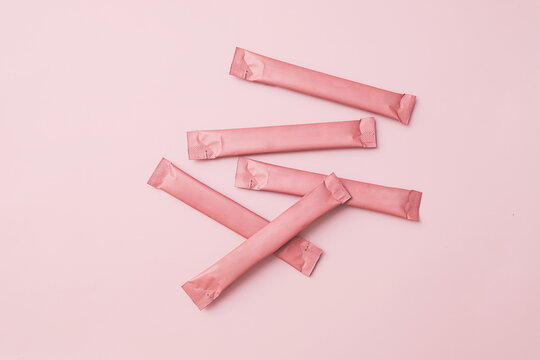 Pink sachets stick packs with copy space on matching pink background. Clean aesthetic for branding.