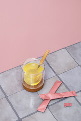 Clear glass with health drink and spoon on a cork coaster next to pink sachets.