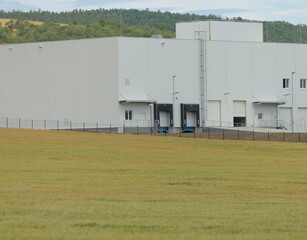 This industrial warehouse features multiple loading docks and a large green field, conveniently...