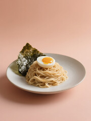 Minimalist noodle dish with a soft-boiled egg and seaweed on a white plate, set against a soft peach background.