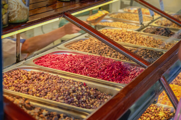 Nut, dried fruits and Spice Market. Metal trays filled with assorted nuts in traditional market stall. Concept of abundance, organic snacks, culinary diversity