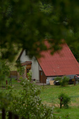 A charming rural house, adorned with a vibrant red roof, is beautifully nestled within lush...