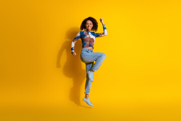 Cheerful woman jumping joyfully in a colorful setting wearing trendy casual outfit, showcasing vibrant energy
