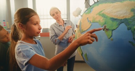 STEM Science Lesson: Smart School Girl Presenting Renewable Energy Sources Using Globe with 3D...
